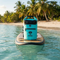 RIXVA 5L light blue waterproof dry bag with roll-top closure and exterior pocket sitting on a paddleboard at the beach